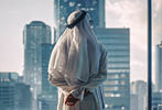 Successful Muslim Businessman in Traditional White Kandura Standing in His Modern Office Looking out of the Window on Big City with Skyscrapers. Successful Saudi, Emirati, Arab Businessman Concept.
